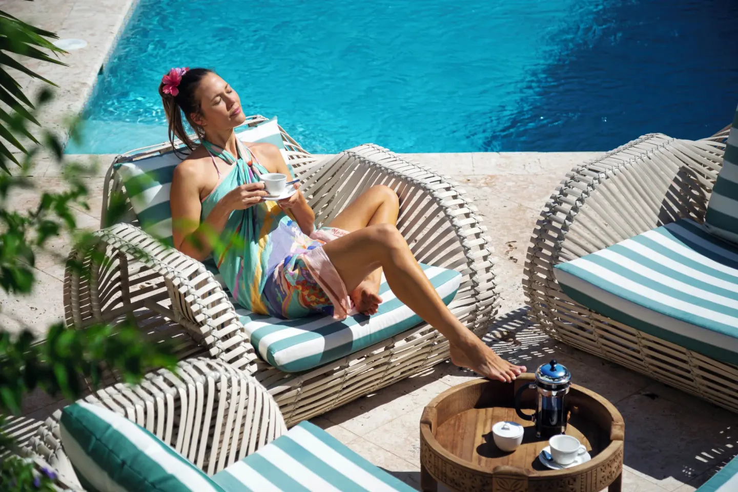 Guest relaxing with coffee beside the pool at Cap Maison Resort & Spa.