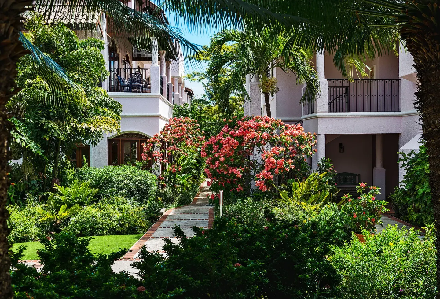 Garden walkway between white resort buildings at Cap Maison Resort & Spa.