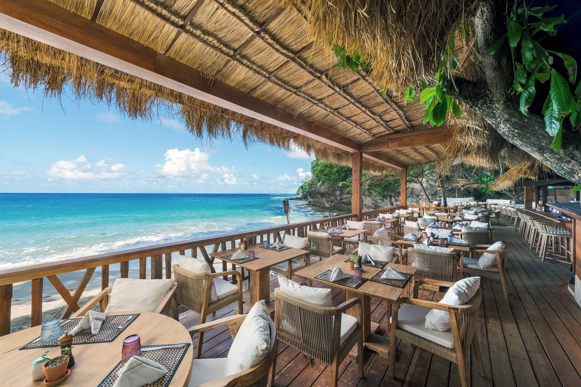 Thatched beachfront restaurant deck with ocean views at Cap Maison Resort & Spa.