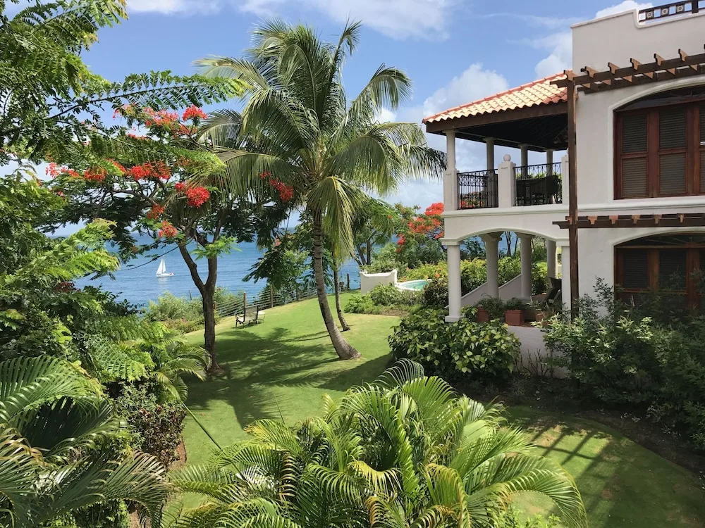 Garden View Room exterior with palms, lawn and sea beyond at Cap Maison Resort & Spa.
