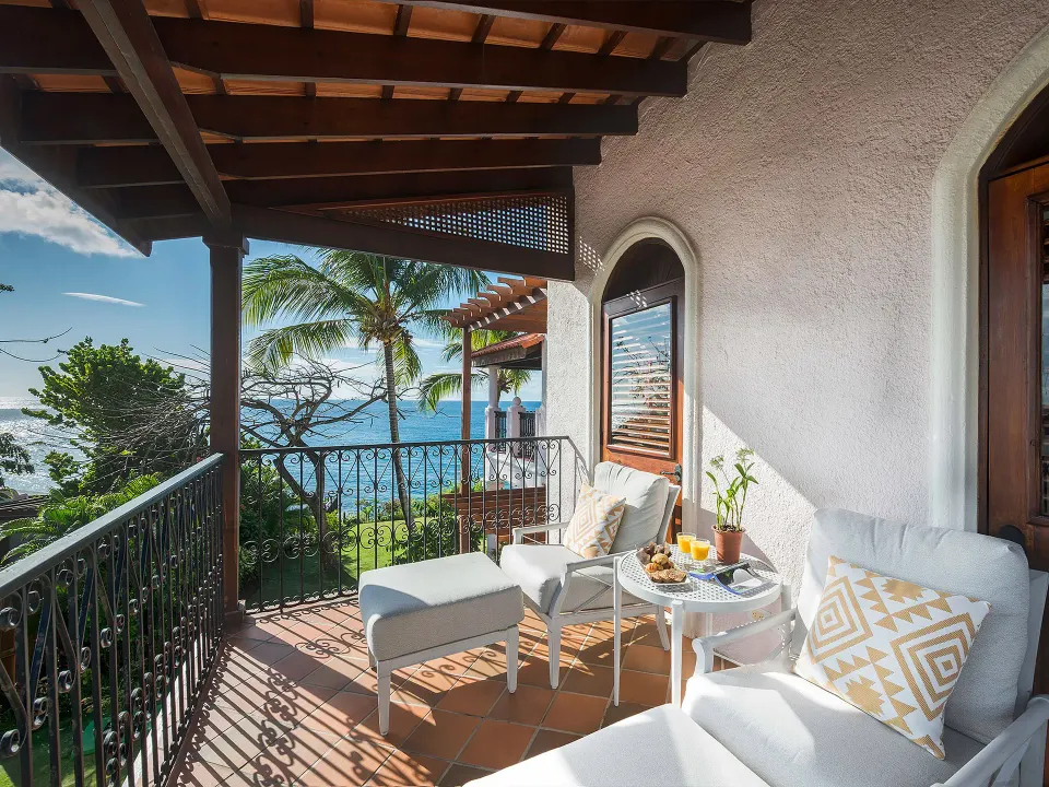 Junior Suite balcony with cushioned chairs and ocean view at Cap Maison Resort & Spa.