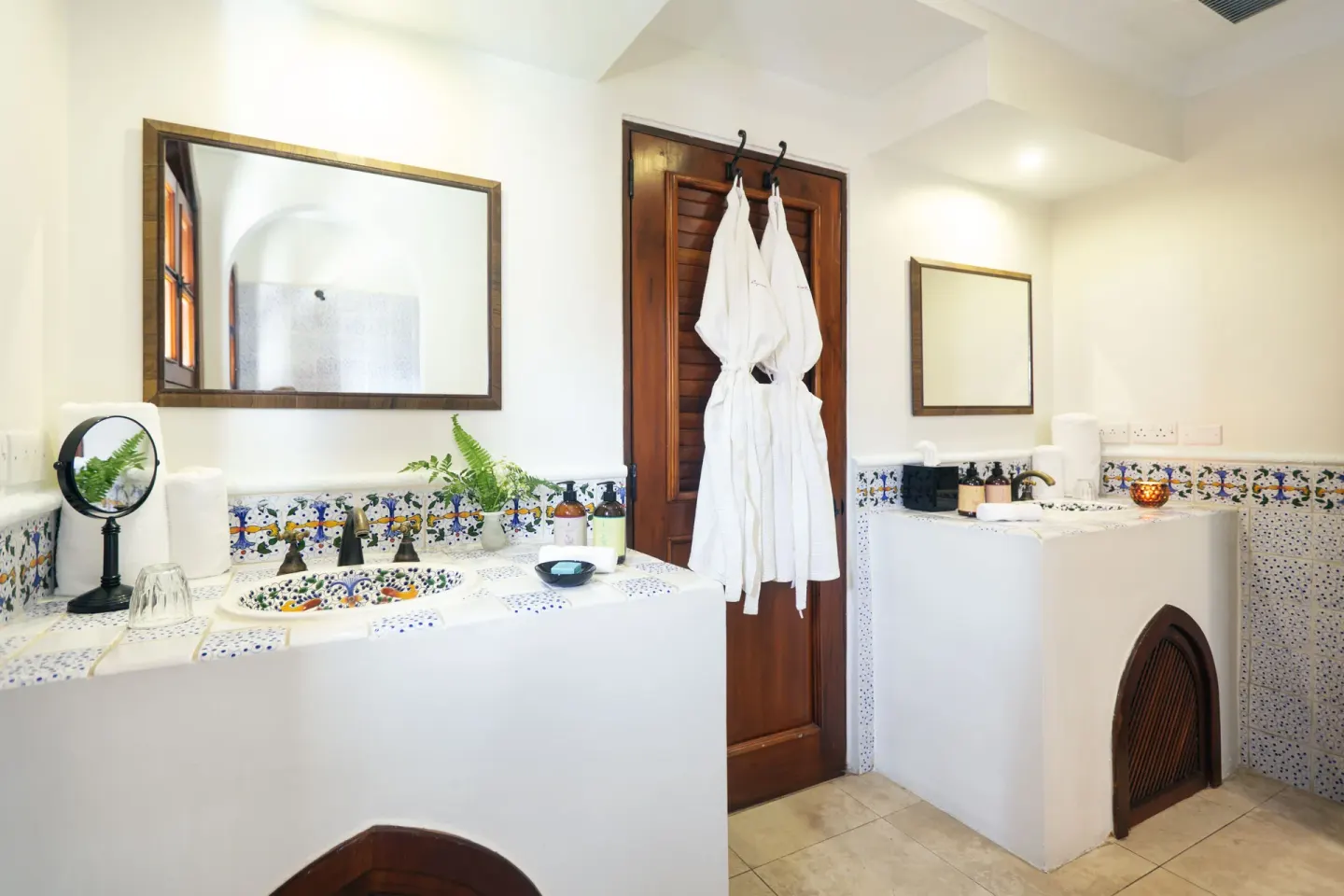 Junior Suite bathroom with twin vanities, robes, and patterned tile at Cap Maison Resort & Spa.