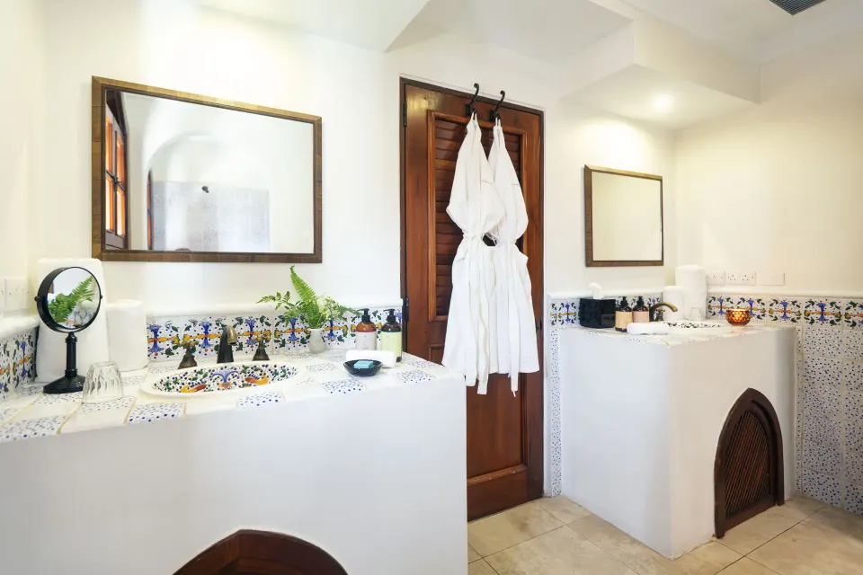 Junior Suite bathroom with twin vanities, robes, and patterned tile at Cap Maison Resort & Spa.