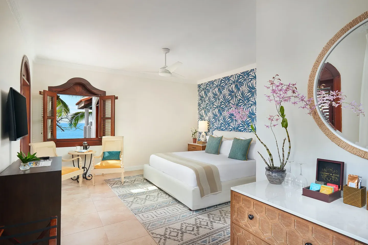 Junior Suite bedroom with king bed, seating area, and sea-facing window at Cap Maison Resort & Spa.