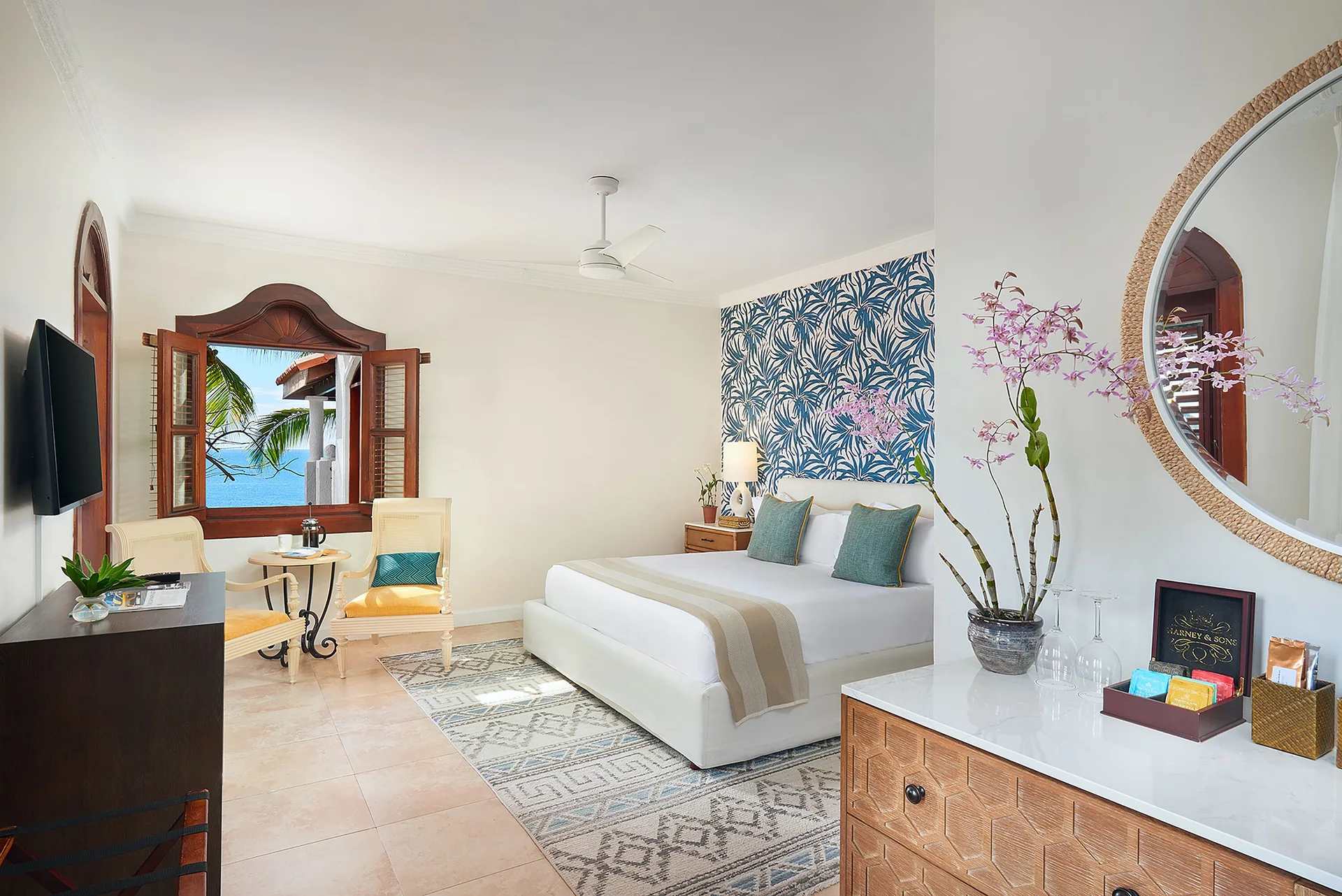 Junior Suite bedroom with king bed, seating area, and sea-facing window at Cap Maison Resort & Spa.