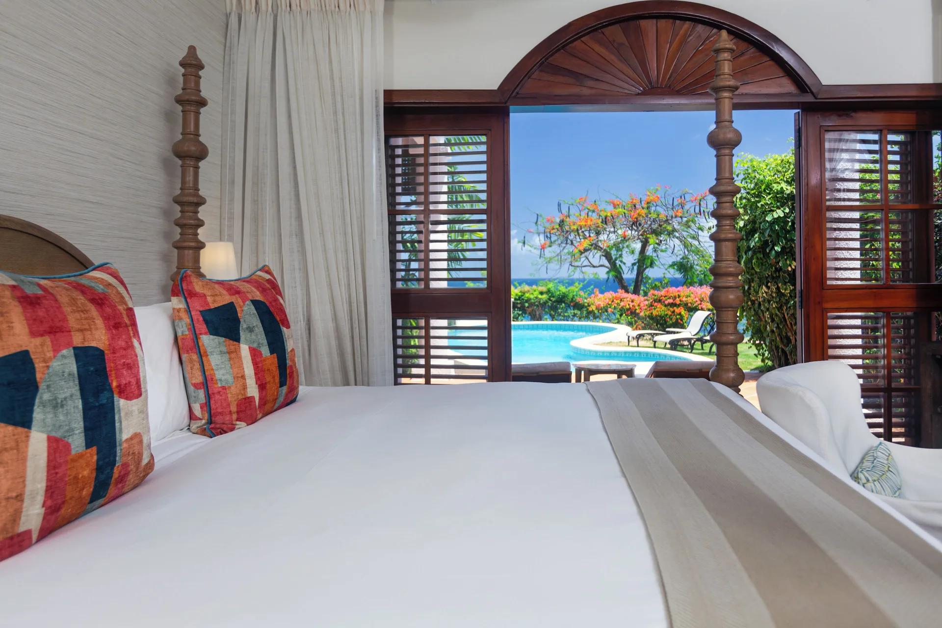 Villa bedroom with four-poster bed opening to a pool and sea view at Cap Maison Resort & Spa.