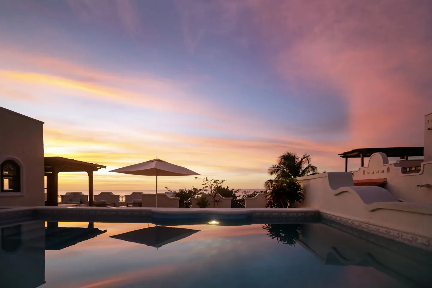 Villa pool at sunset with terrace walls and umbrella at Cap Maison Resort & Spa.