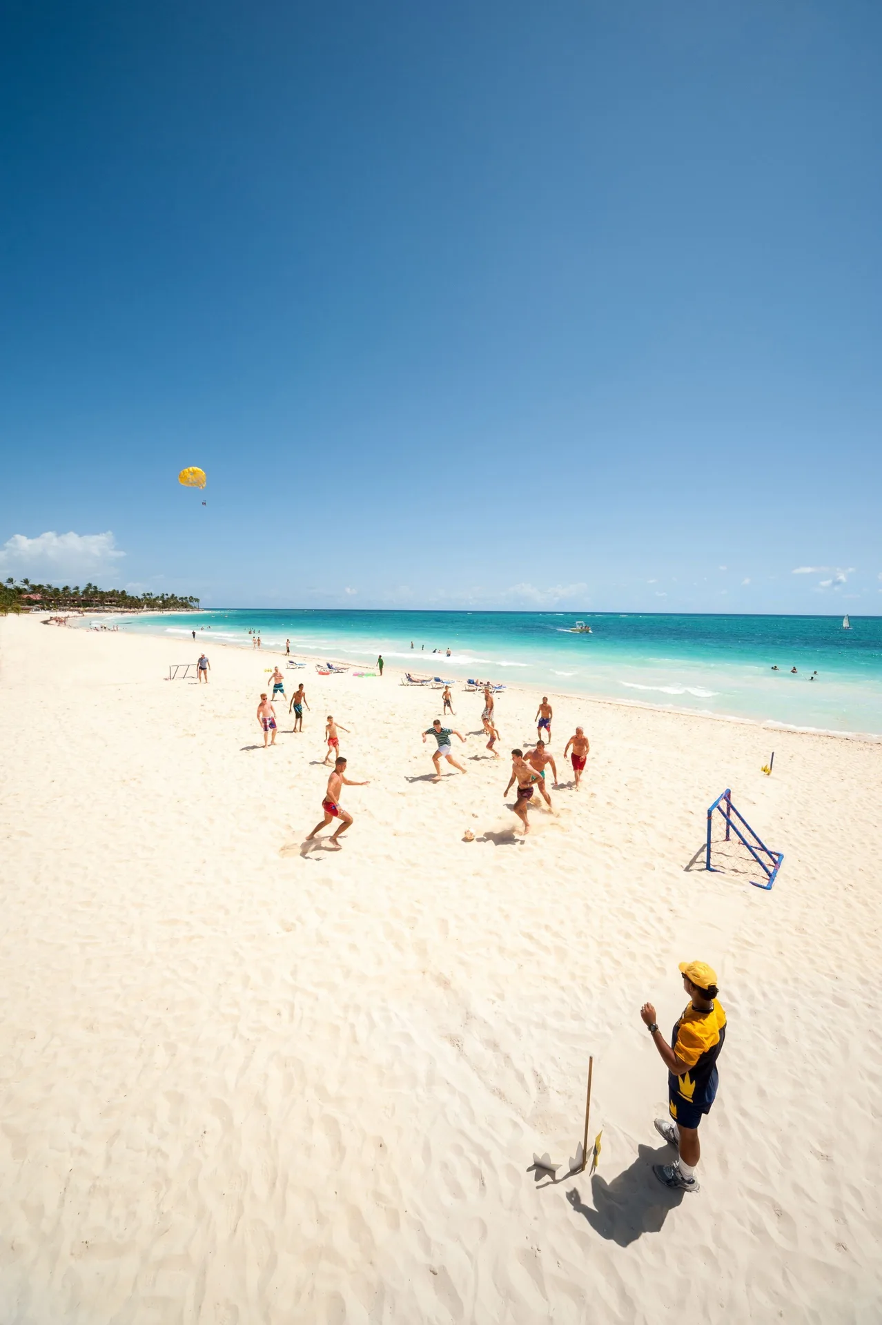 Guests play beach soccer on white sand by turquoise water at Caribe Deluxe Princess.