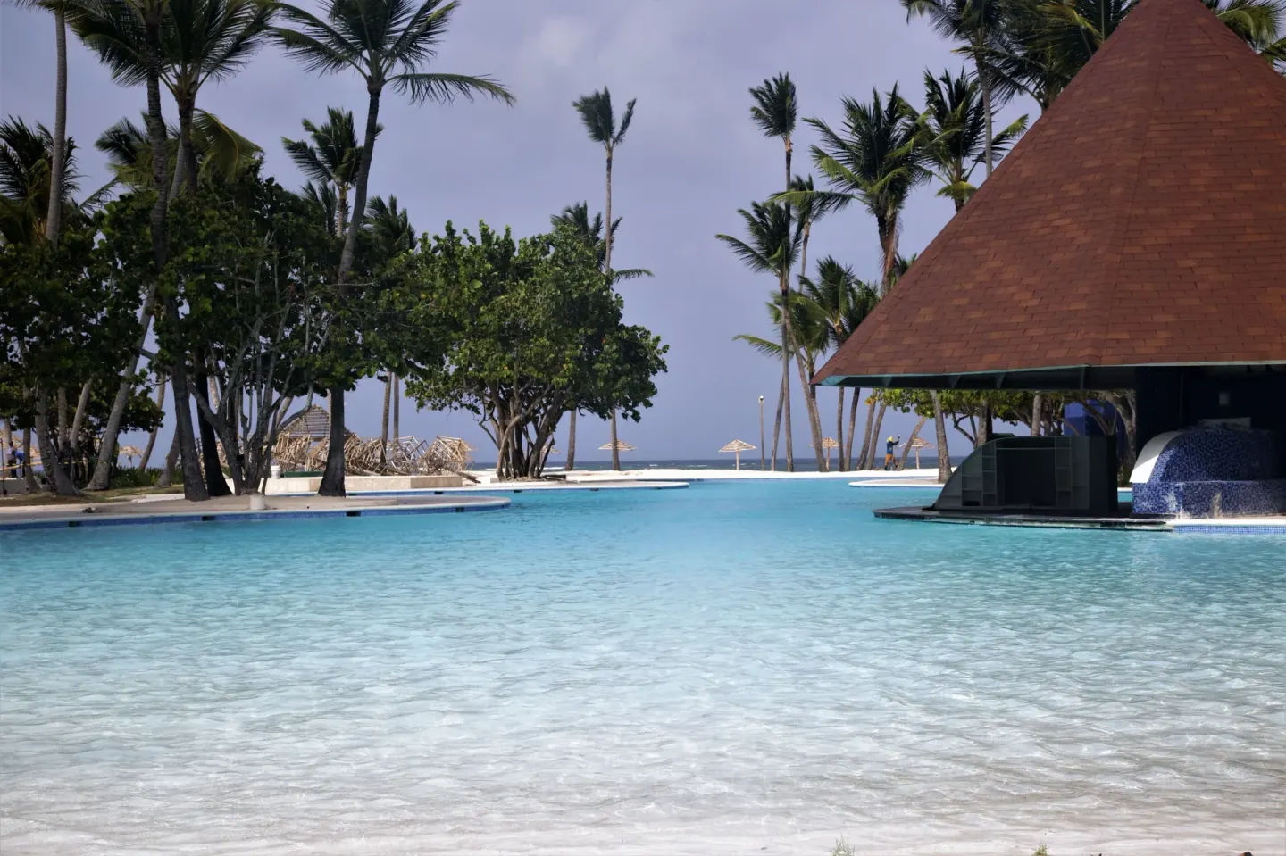 Shallow pool with ocean beyond and a roofed pavilion at Caribe Deluxe Princess.