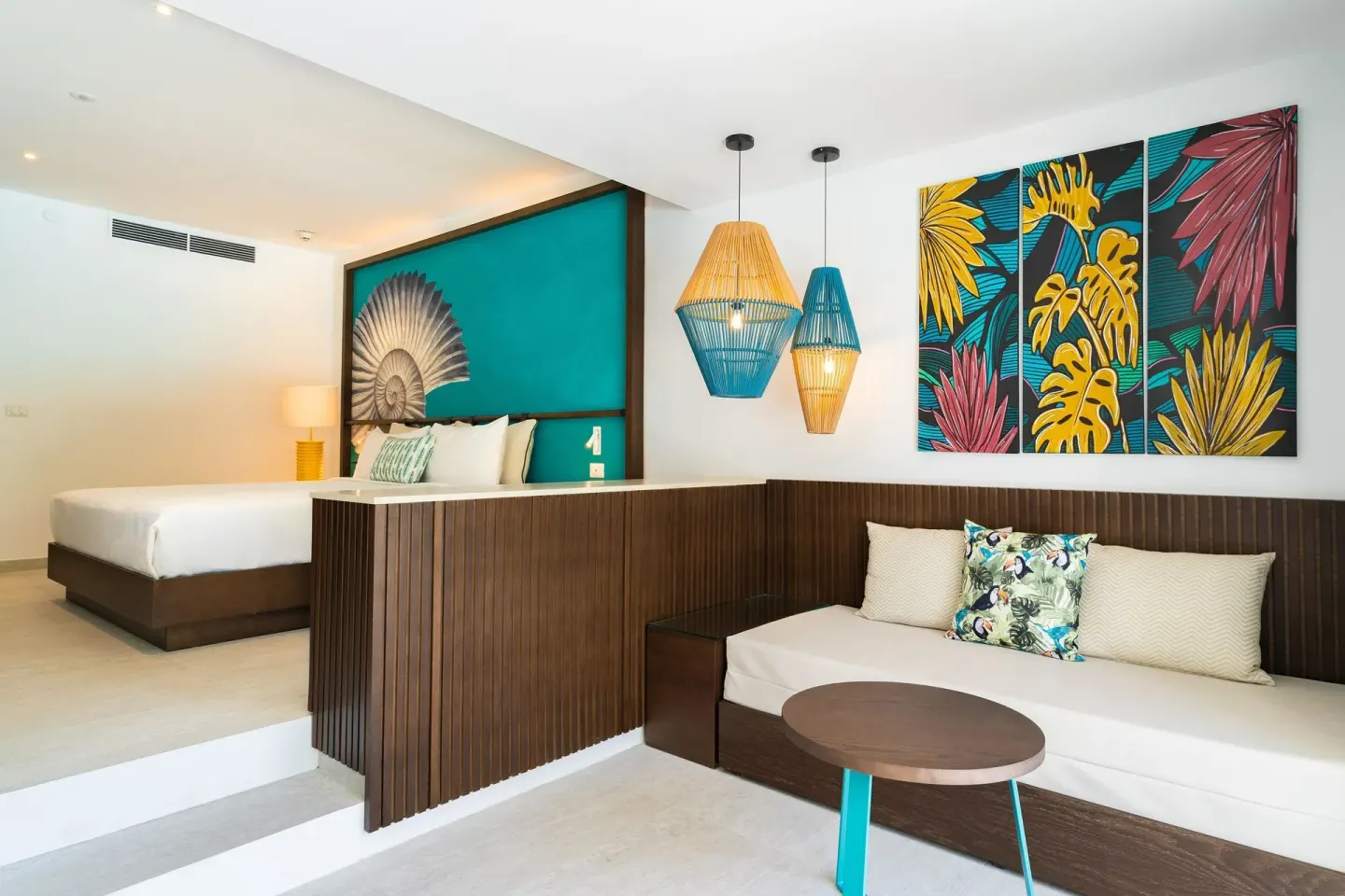 King bed suite with sitting area and tropical wall art at Caribe Deluxe Princess.