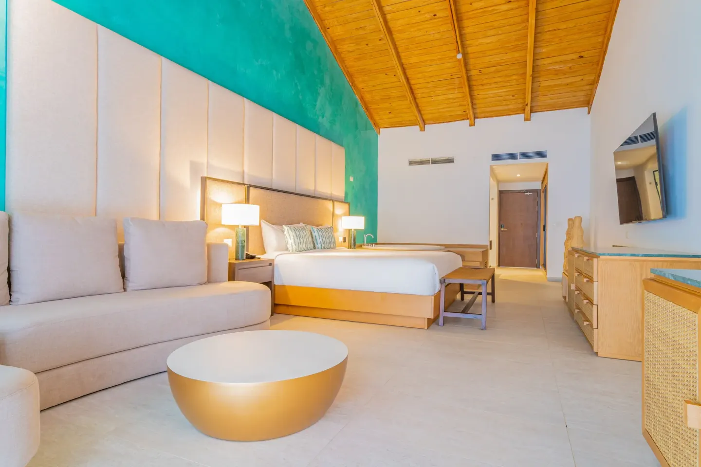 Guest room with king bed, sofa and wood ceiling at Caribe Deluxe Princess.