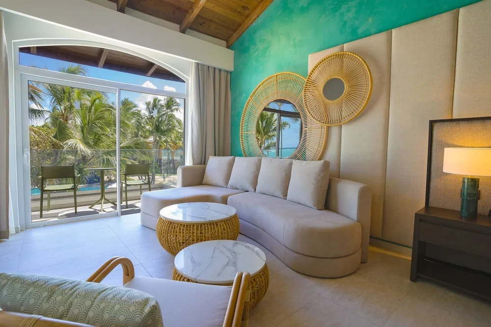 Guest room lounge with sofa and balcony view of palms at Caribe Deluxe Princess.