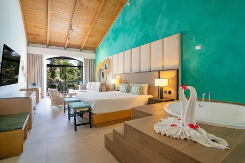 Guest room with two beds, soaking tub, and vaulted wood ceiling at Caribe Deluxe Princess.