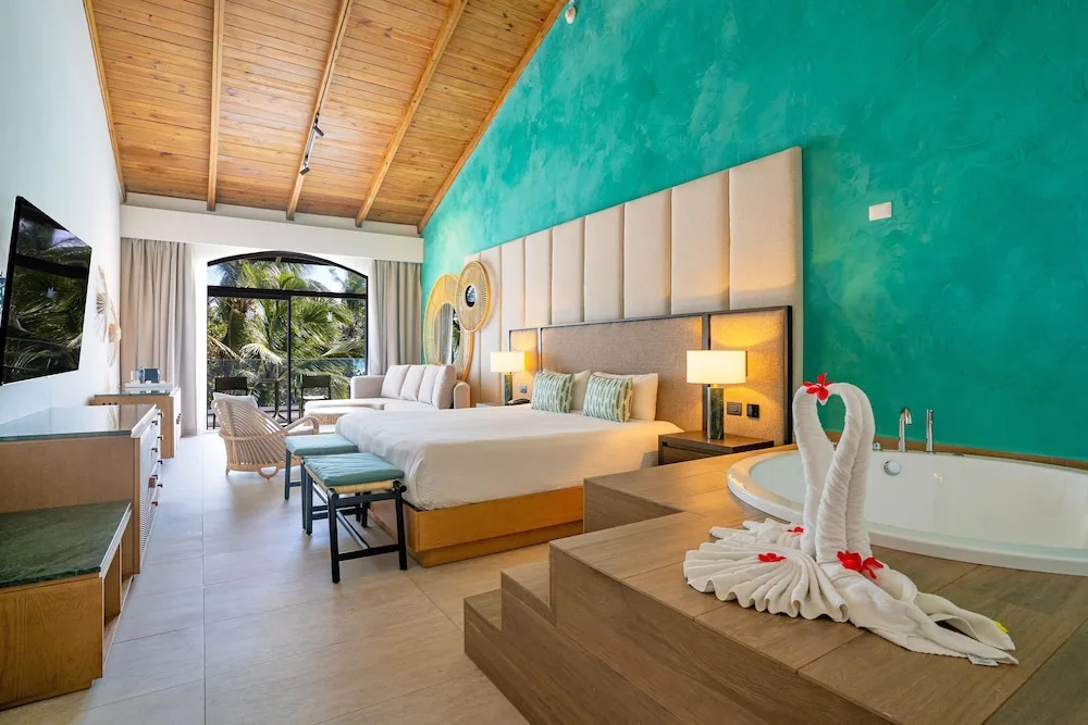 Guest room with two beds, soaking tub, and vaulted wood ceiling at Caribe Deluxe Princess.