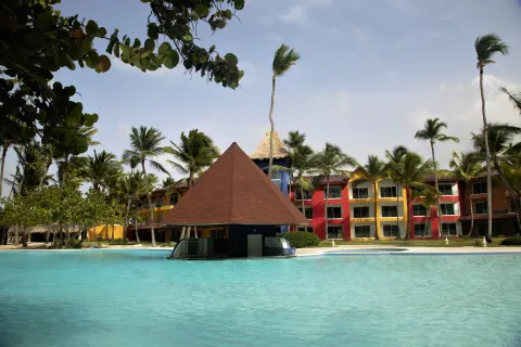 Pool bar pavilion with palms and colorful buildings at Caribe Deluxe Princess.