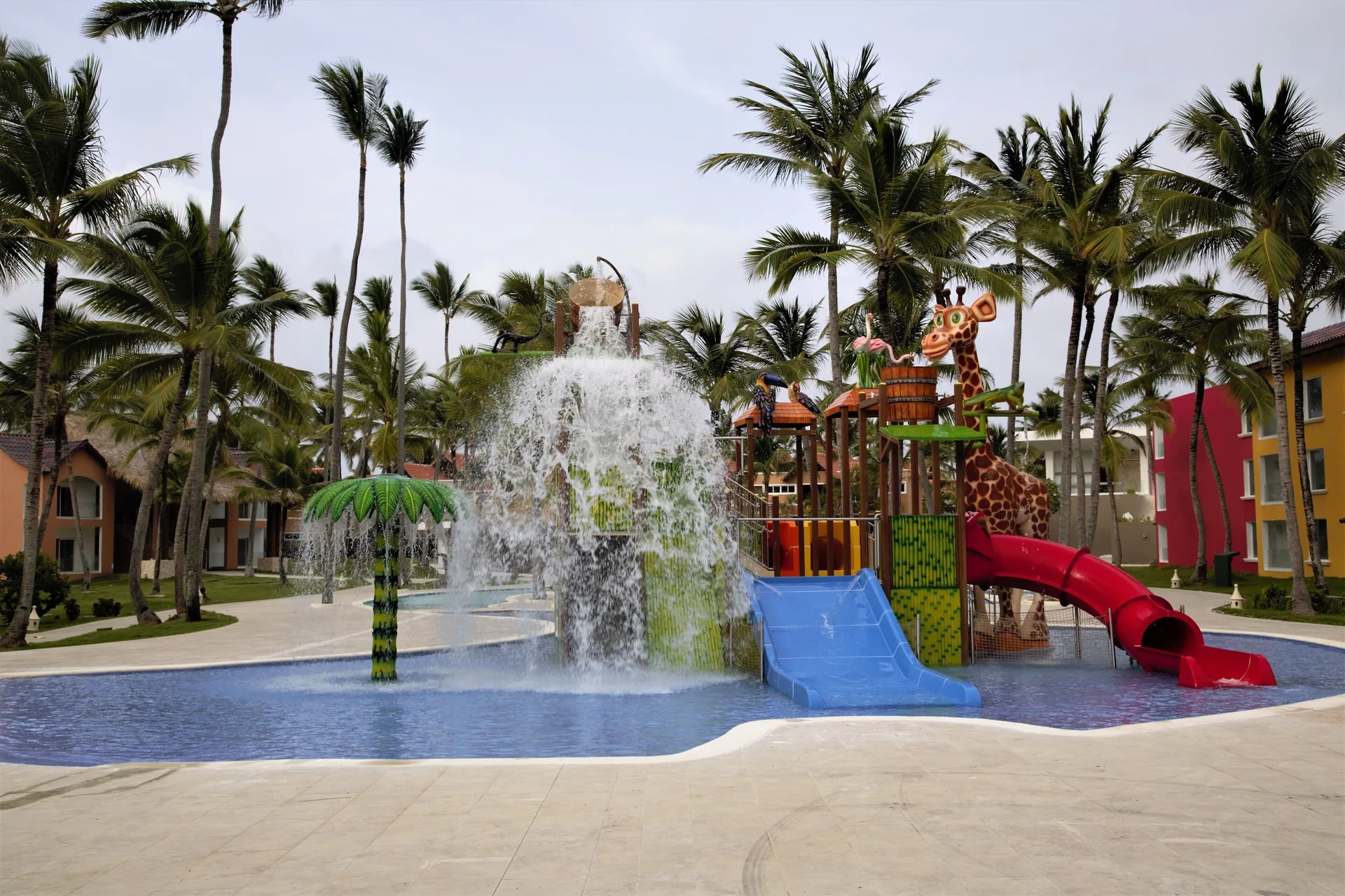 Splash play area with water bucket, slides, and giraffe figure at Caribe Deluxe Princess.