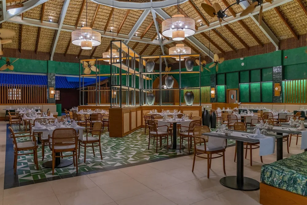 Large thatched-roof dining room with set tables at Caribe Deluxe Princess.