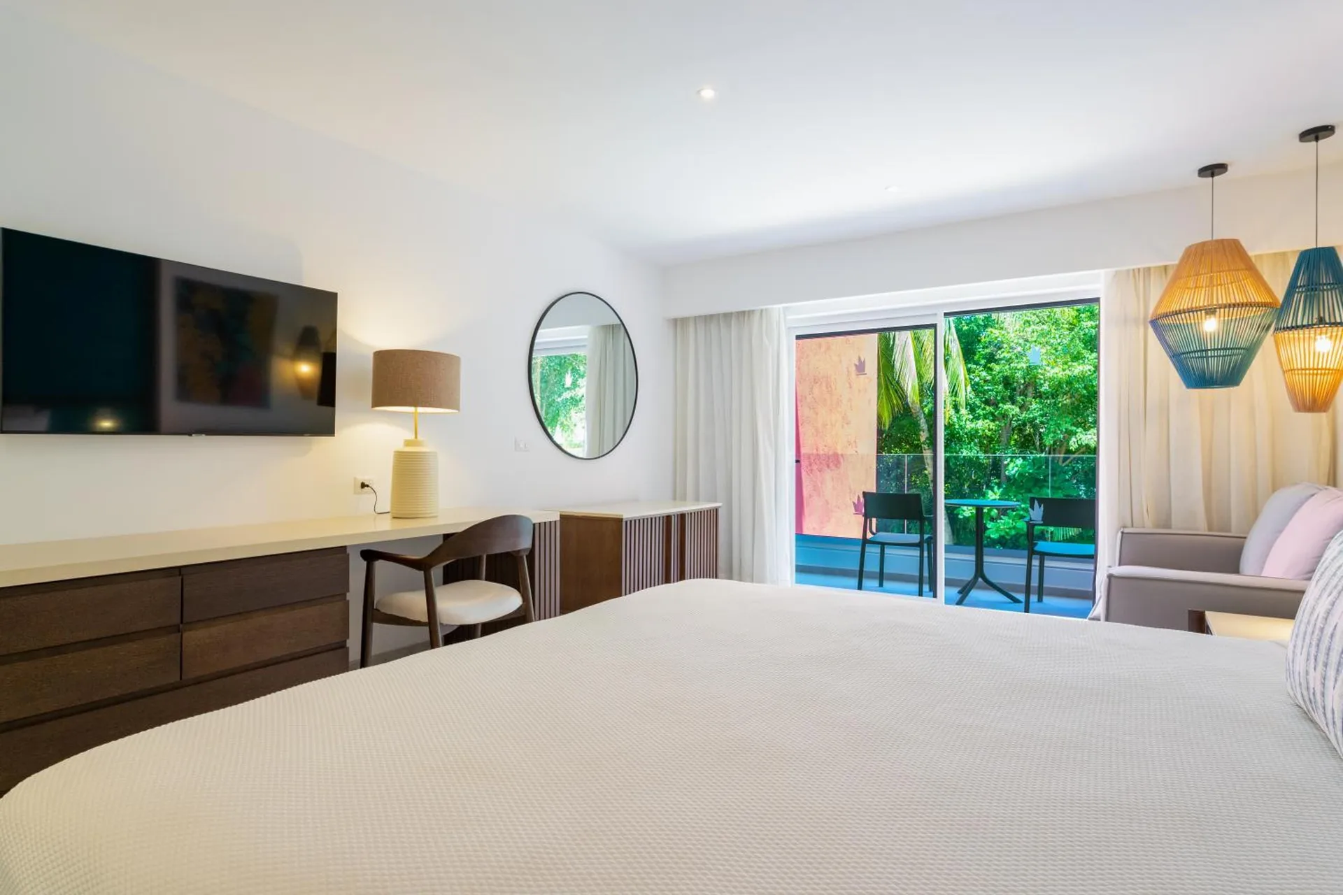 King bed facing desk, TV, and balcony seating at Caribe Deluxe Princess.