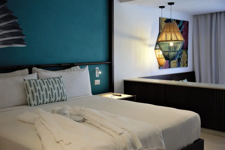 Grand Room bed with robes and pendant lights at Caribe Deluxe Princess.