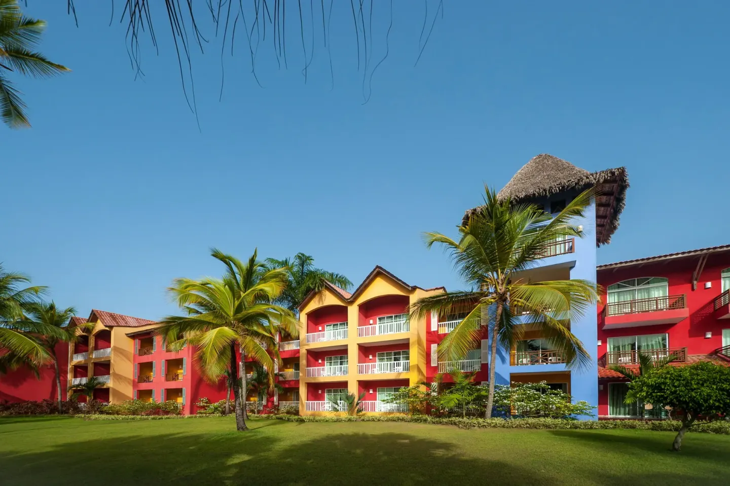 Colorful guest room buildings and palms at Caribe Deluxe Princess.