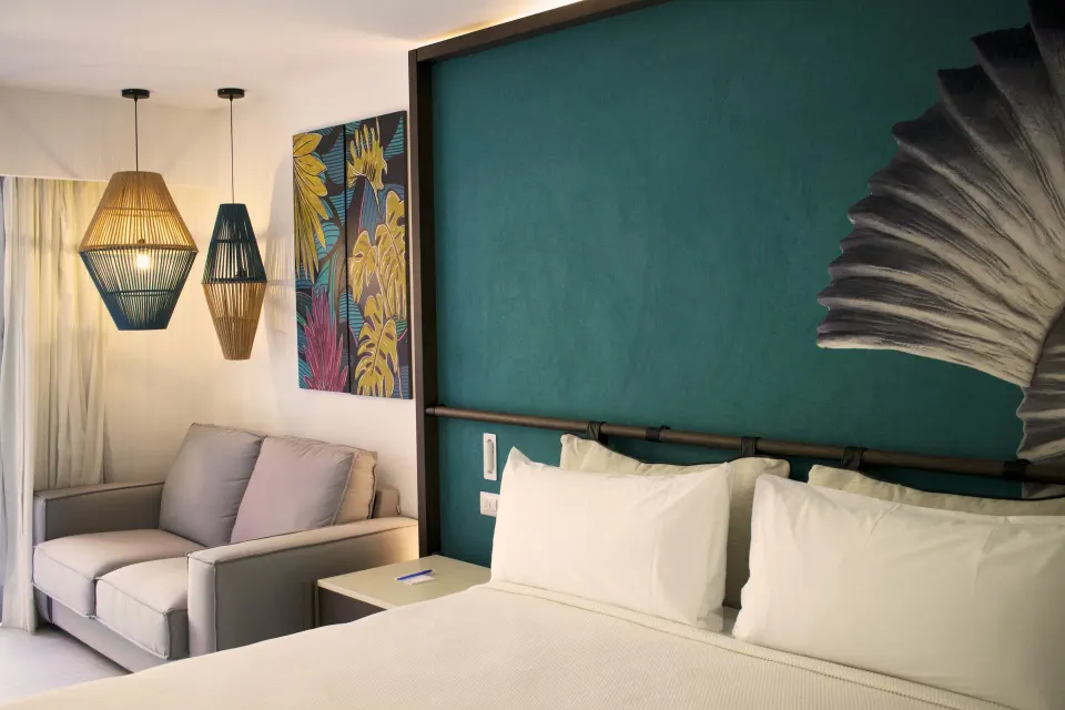 Superior Room bed close-up with sofa corner and hanging lamps at Caribe Deluxe Princess.