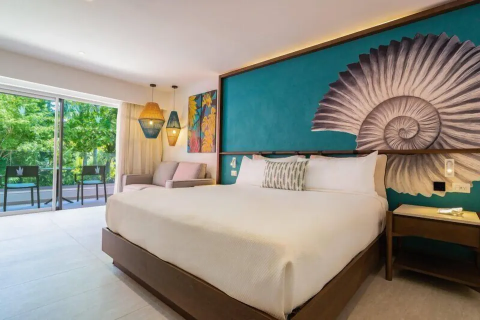 Superior Room king bed with shell mural and balcony at Caribe Deluxe Princess.