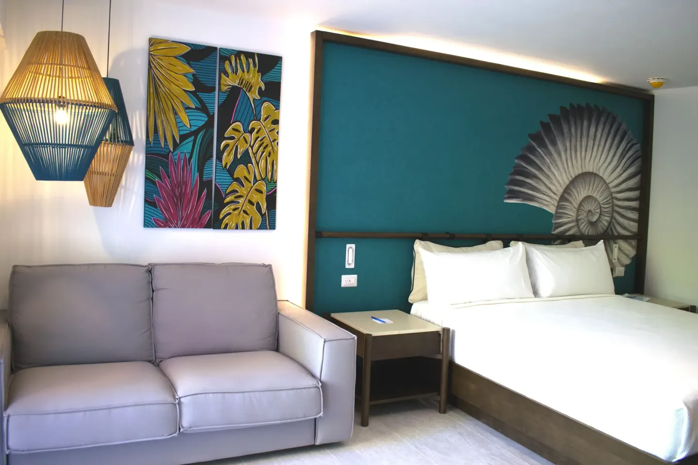 Superior Room king bed and sofa under colorful tropical artwork at Caribe Deluxe Princess.