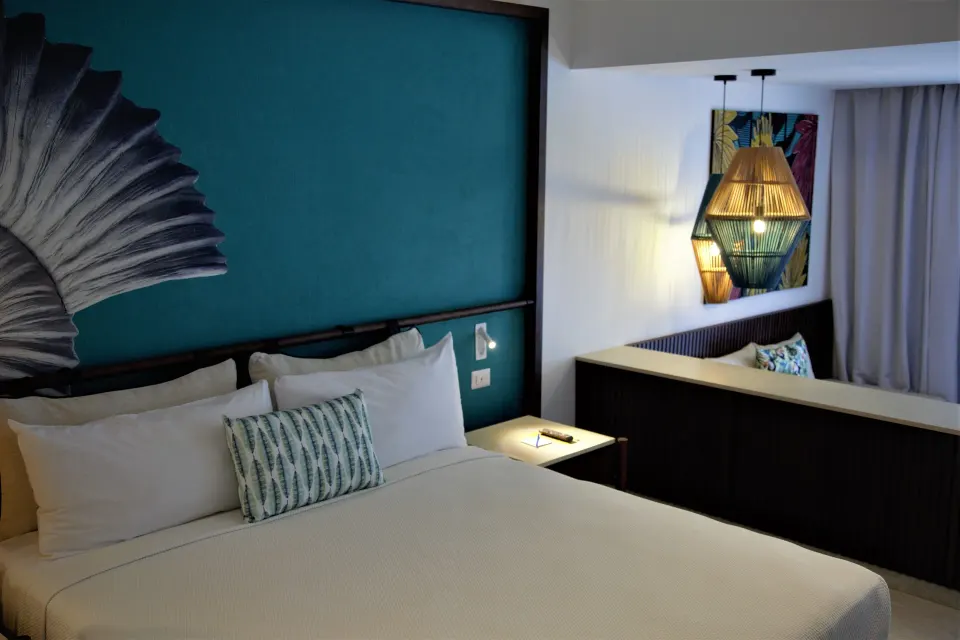 Superior Room king bed with teal shell headboard and sitting area at Caribe Deluxe Princess.