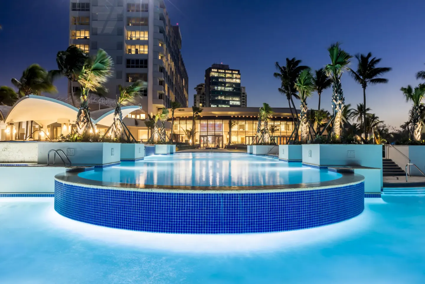 Illuminated pool and resort buildings at dusk at Caribe Hilton.