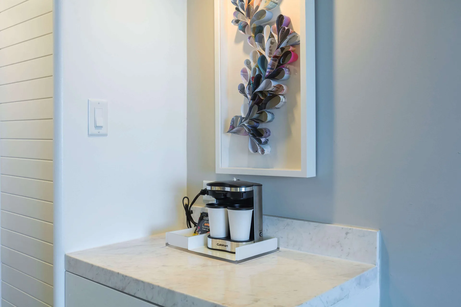 In-room coffee maker on a marble counter beneath framed wall art at Caribe Hilton.
