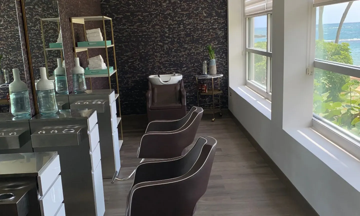 Salon chairs and wash station beside ocean-facing windows at Caribe Hilton.