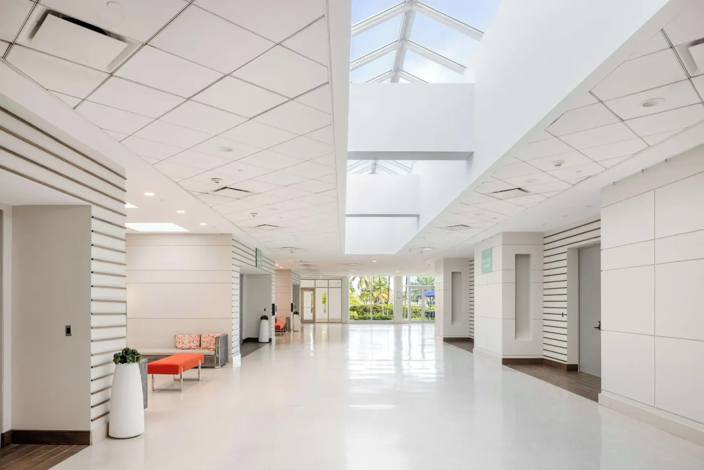 A bright corridor with skylights, white walls, and lounge benches at Caribe Hilton.