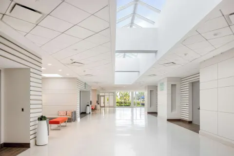 A bright corridor with skylights, white walls, and lounge benches at Caribe Hilton.