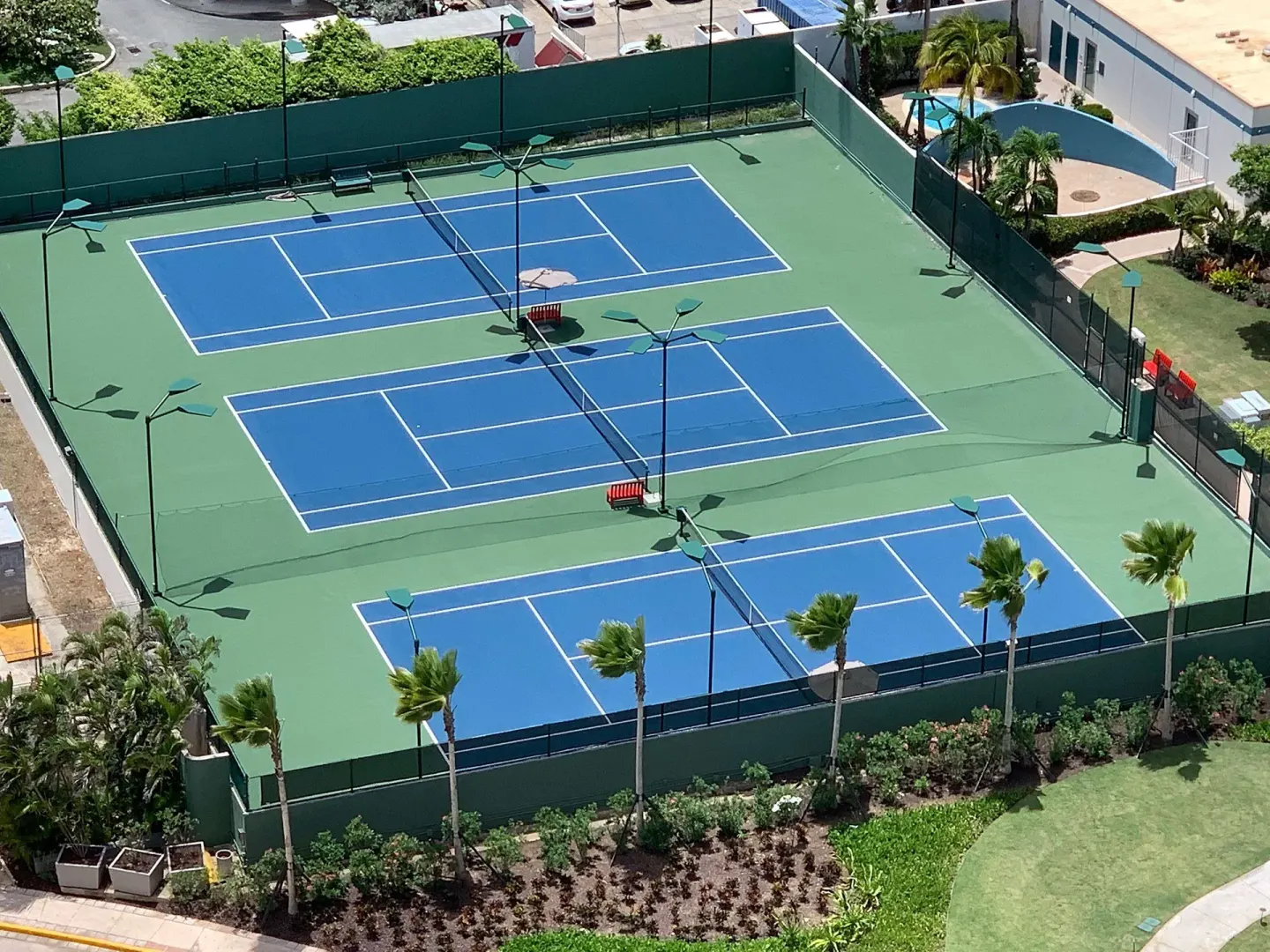 Three blue tennis courts viewed from above at Caribe Hilton.