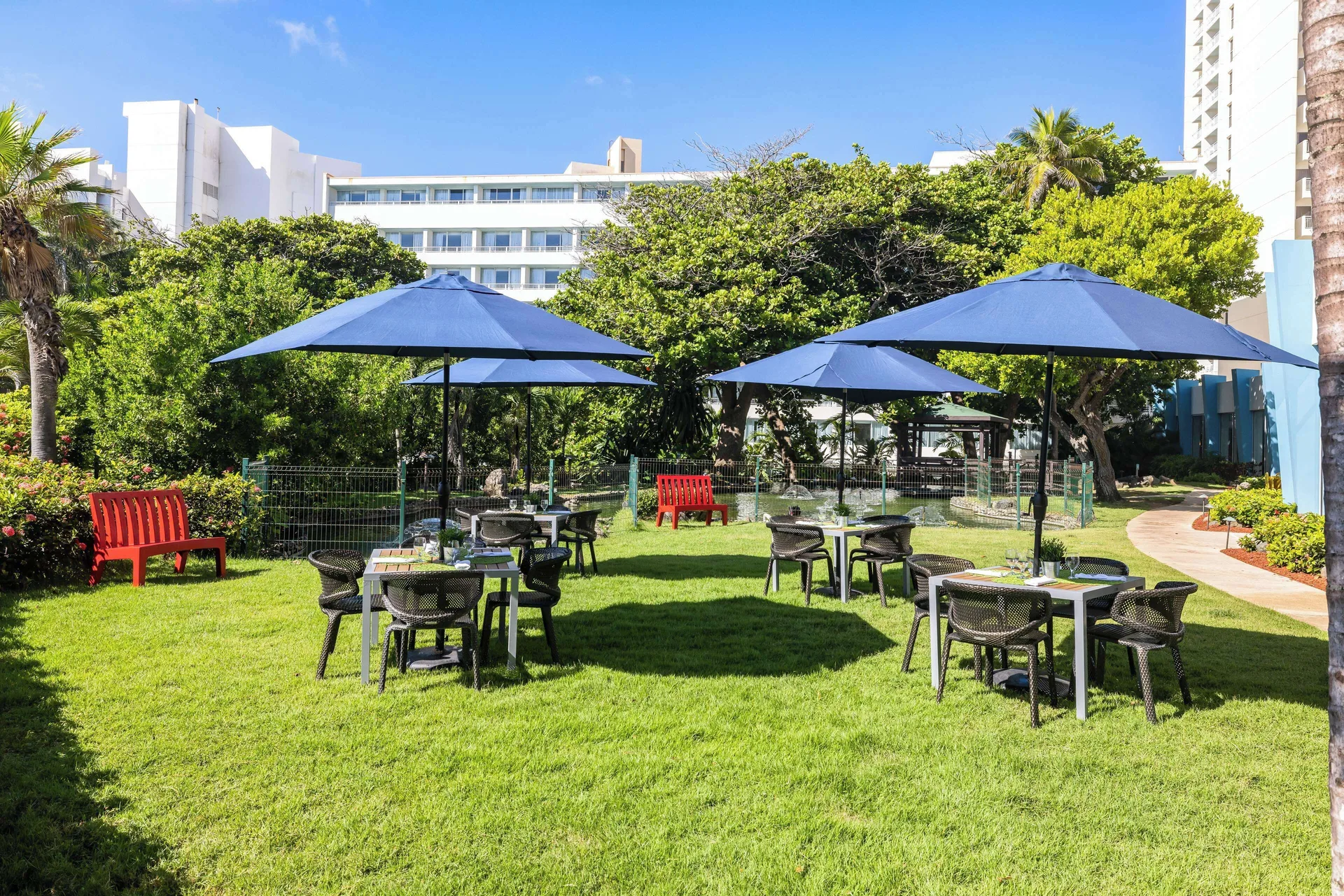 Garden dining tables with blue umbrellas on the lawn at Caribe Hilton.