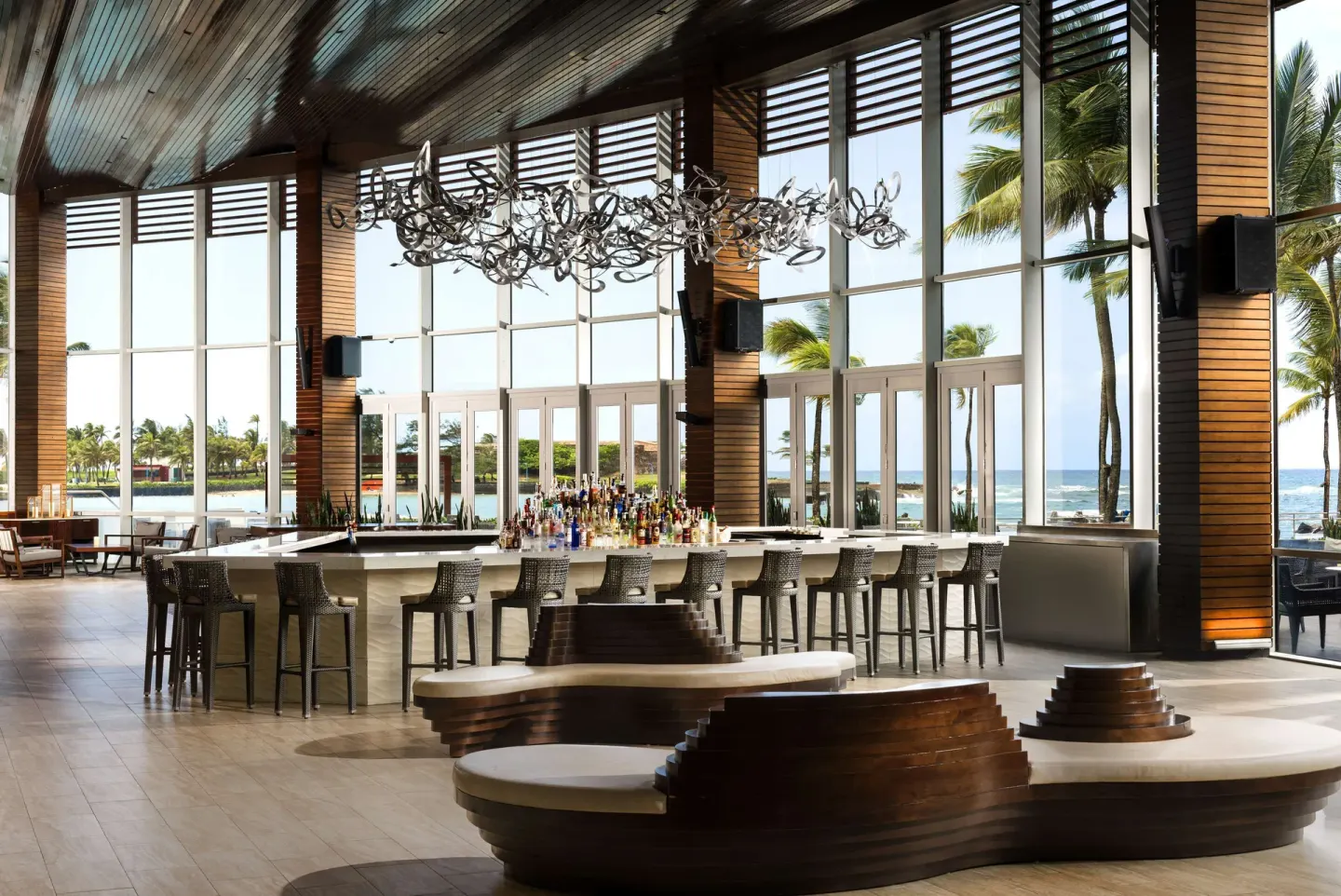Open bar lounge with ocean-facing windows and high stools at Caribe Hilton.