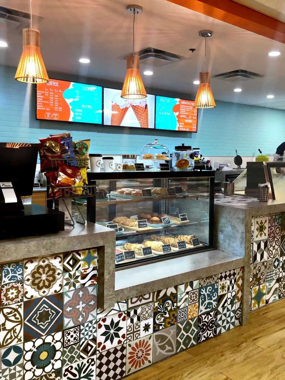 Cafe counter with pastries, cookies, and menu boards at Caribe Hilton.
