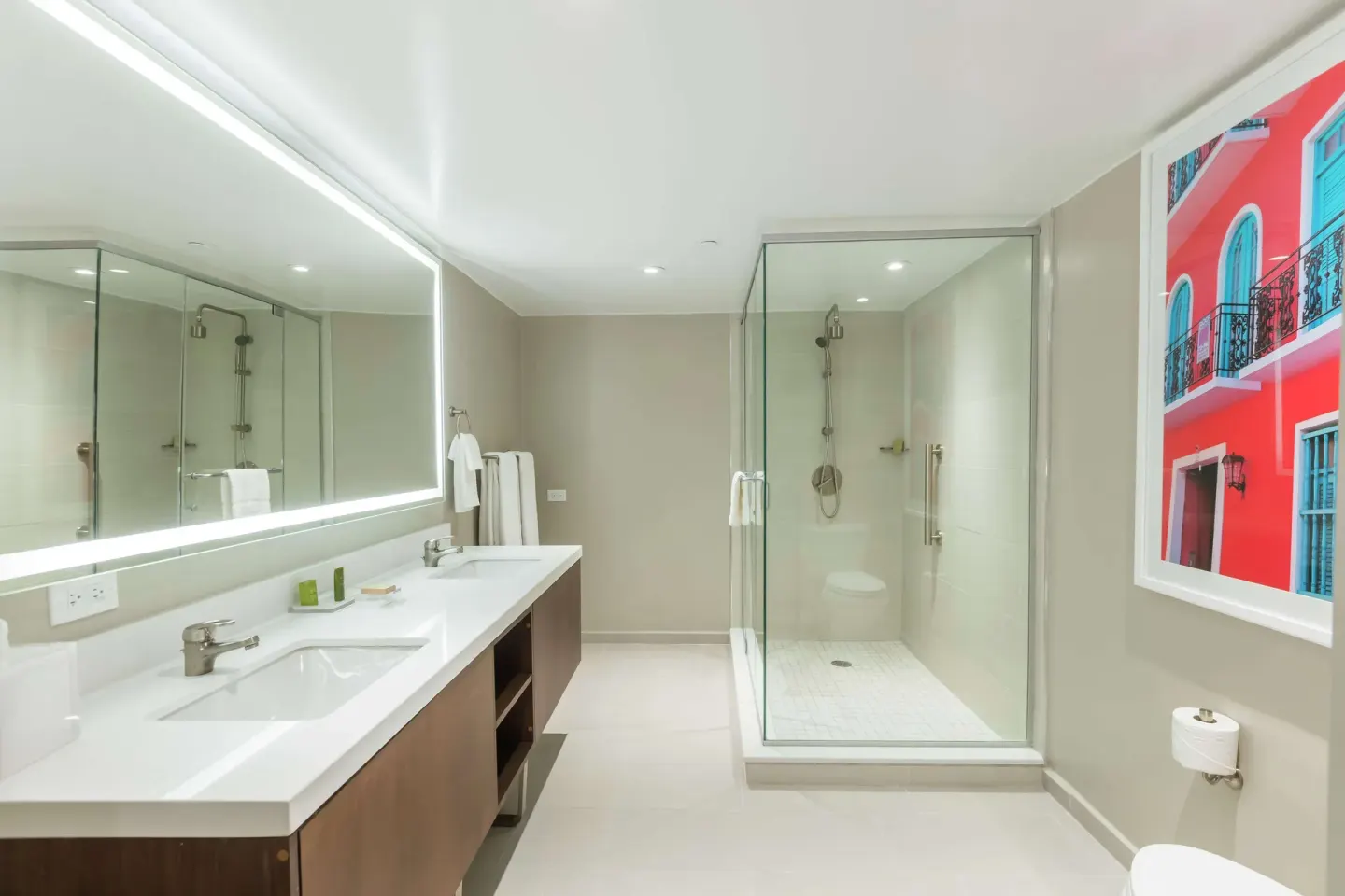 Suite bathroom with double vanity, illuminated mirror, and glass shower at Caribe Hilton.