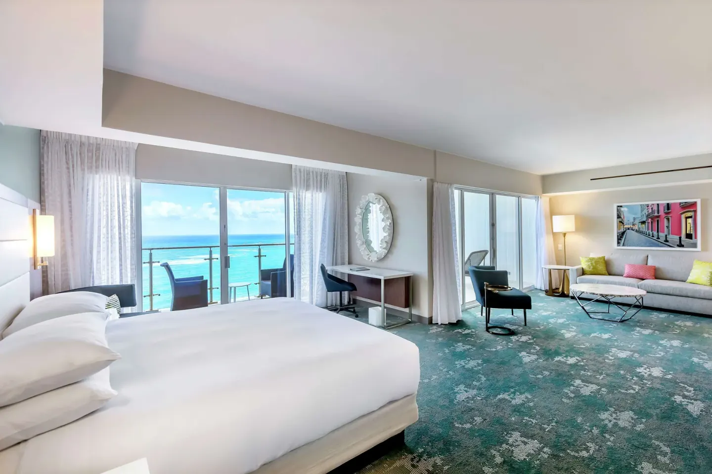 King bedroom with ocean-facing balcony and sitting area in a suite at Caribe Hilton.