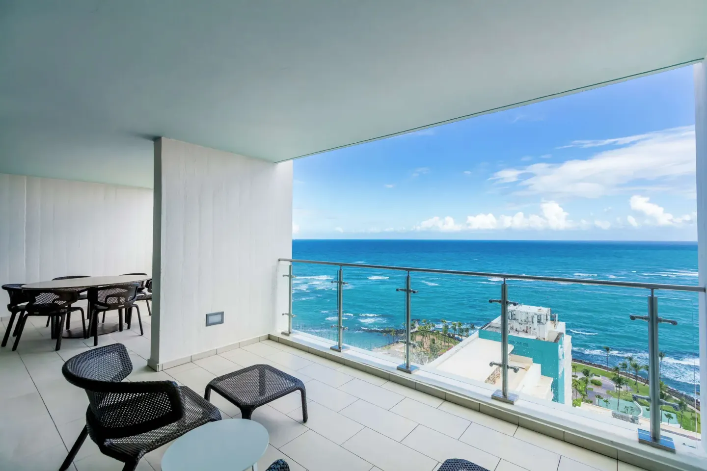 Ocean-view balcony with lounge chairs and dining table in a bi-level suite at Caribe Hilton.