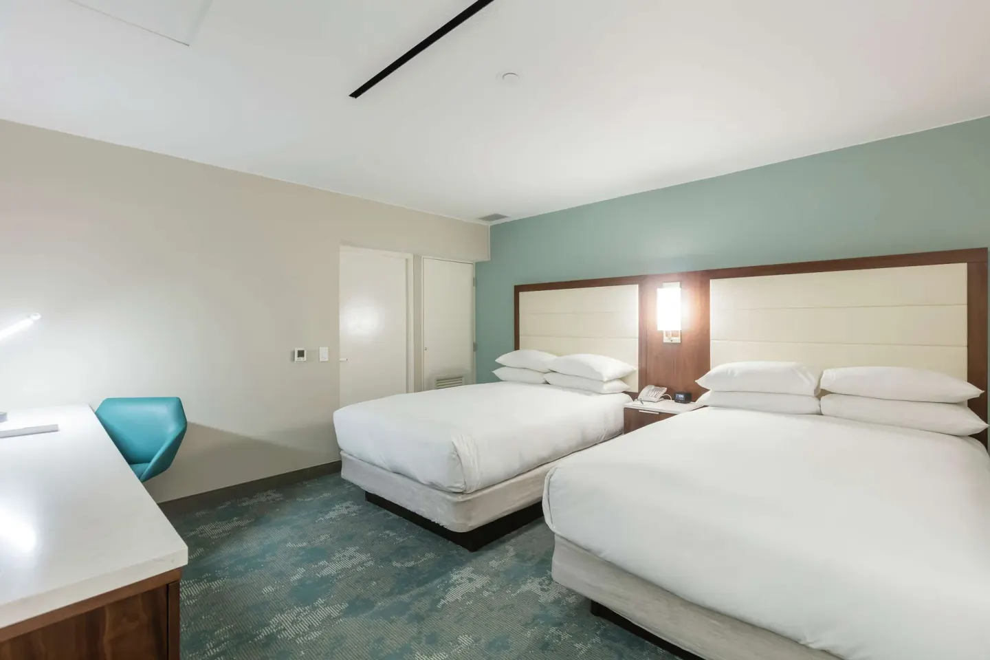 Bedroom with two double beds, desk, and teal chair in a suite at Caribe Hilton.