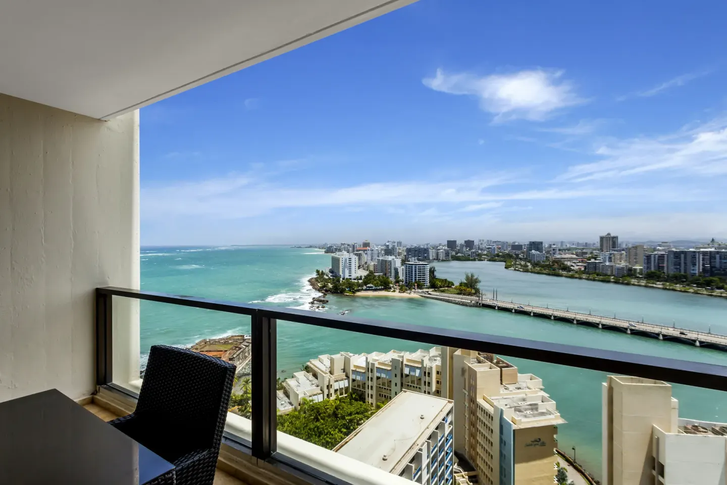 Balcony view from a two-bedroom bi-level suite at Caribe Hilton overlooking ocean, lagoon and city skyline.