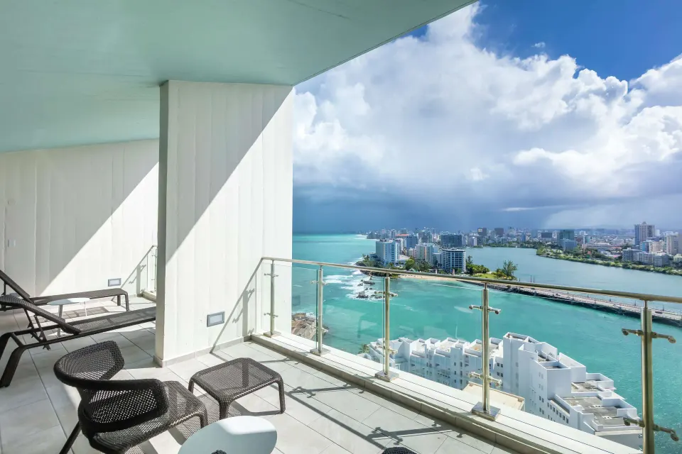 Suite balcony with lounge chairs and turquoise water view at Caribe Hilton.