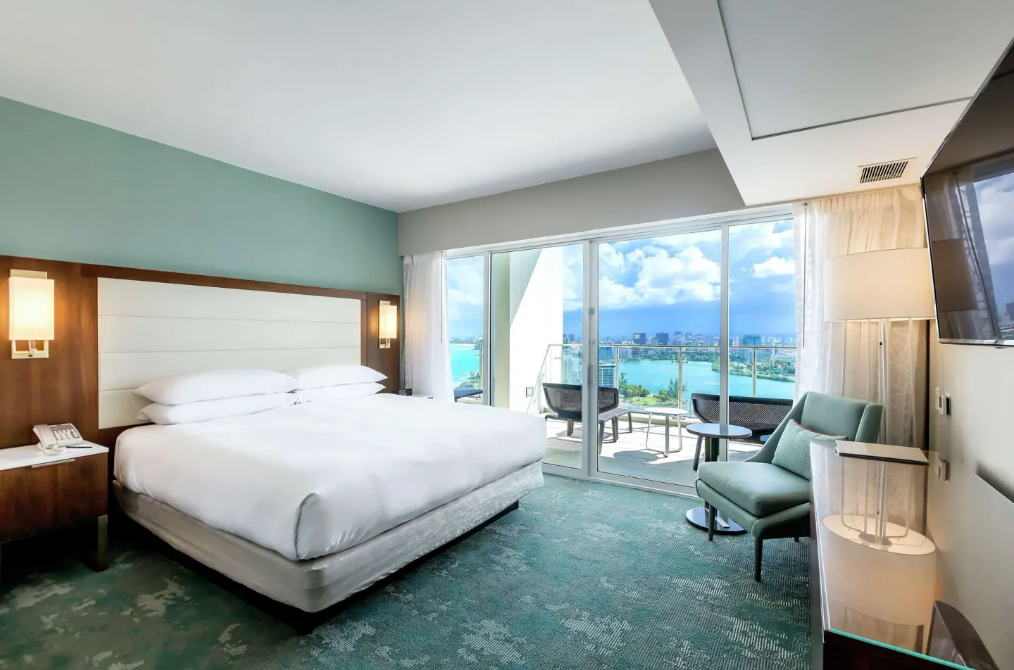 King bedroom with balcony seating and water view at Caribe Hilton.