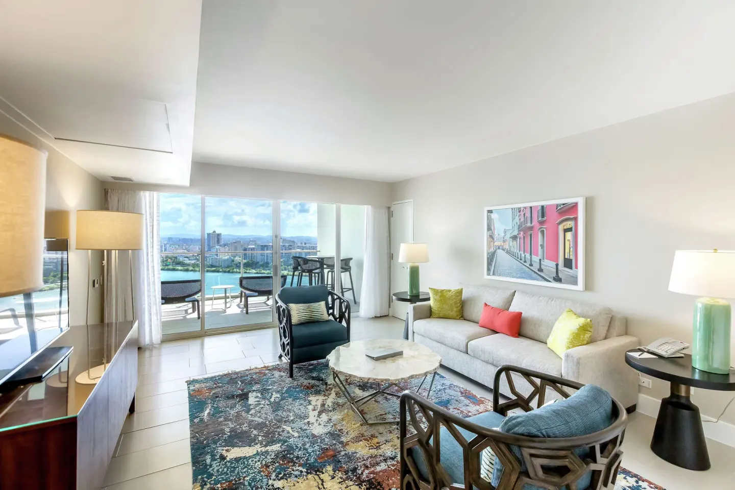 Living room with sofa, chairs, balcony doors, and water view at Caribe Hilton.