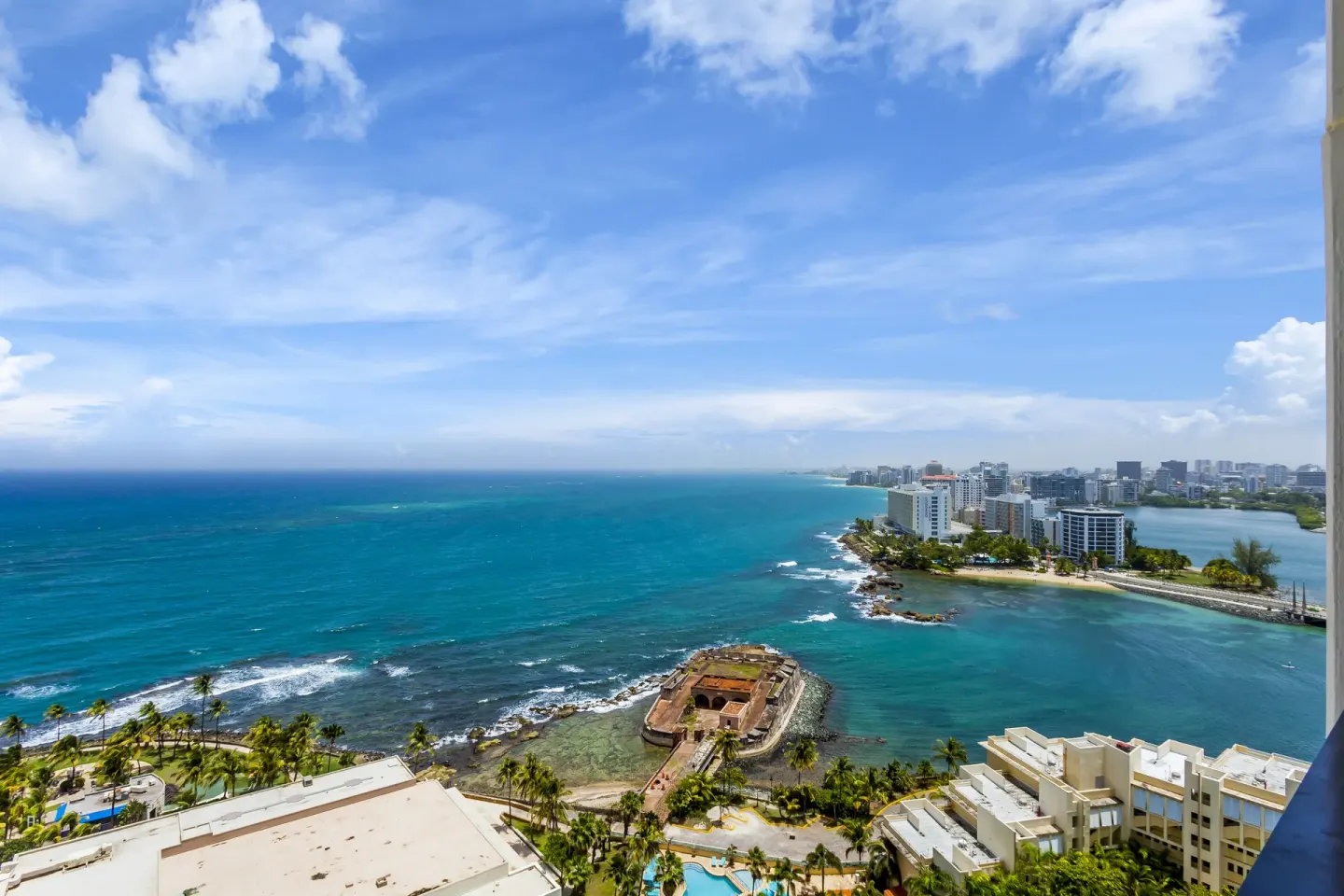 Ocean and coastline view from a two-bedroom bi-level suite at Caribe Hilton with historic fort below.