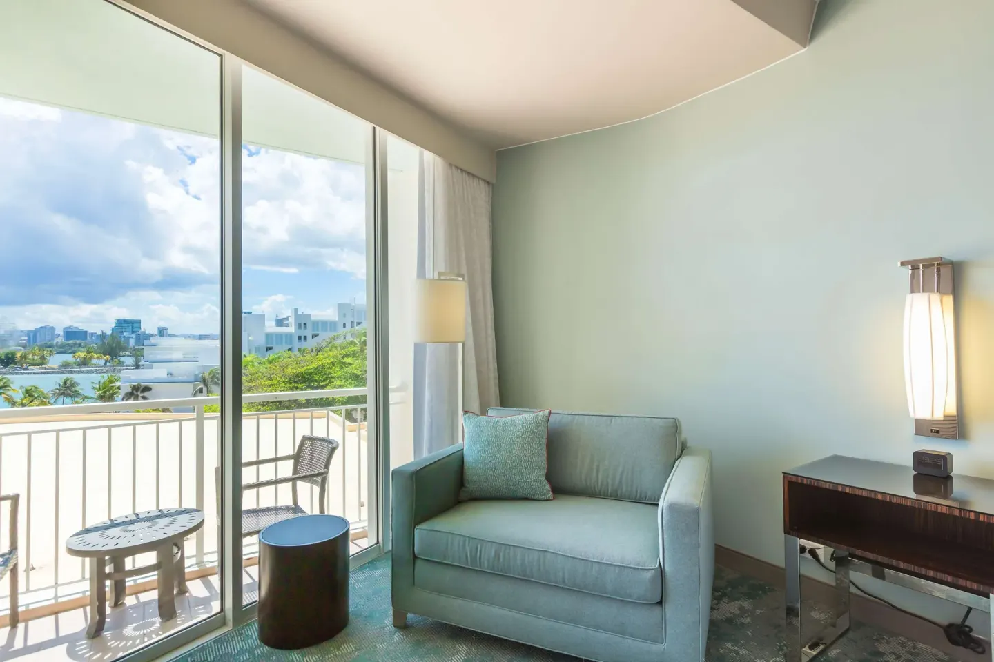 Guest room sitting area with balcony and water view at Caribe Hilton.