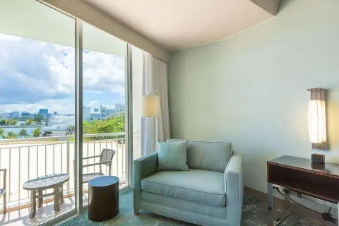 Guest room sitting area with balcony and water view at Caribe Hilton.