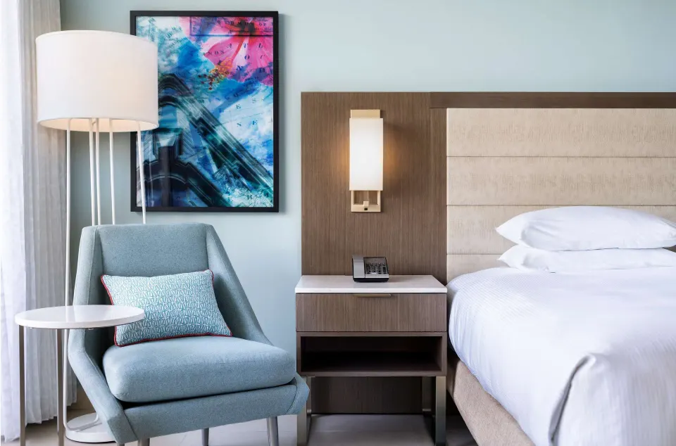 Premium Garden View king bed and lounge chair in a Caribe Hilton guest room.