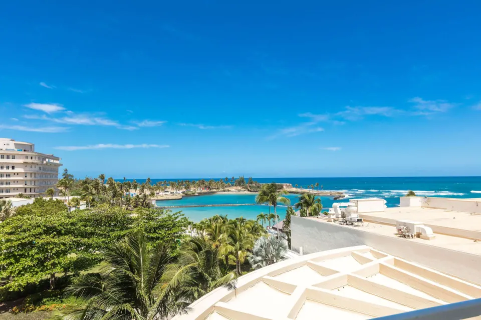 Ocean, lagoon, palms, and rooftops viewed from a guest room at Caribe Hilton.